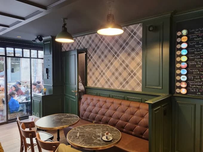 La salle : banquette de cuir capitonné, tables de marbre, boiseries vert profond et papier peint tartan.